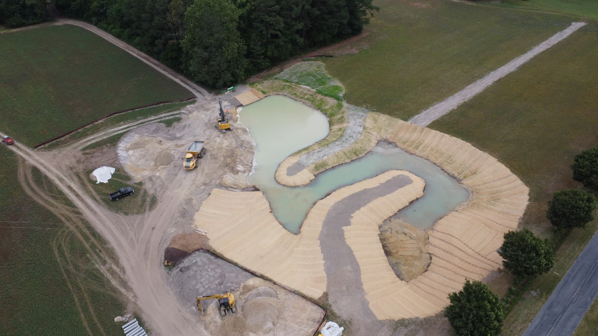 Aerial view of the Denton, Maryland treatment wetland under construction, showing sinuous planted wetland cells and freshly stabilized banks set within an agricultural field.